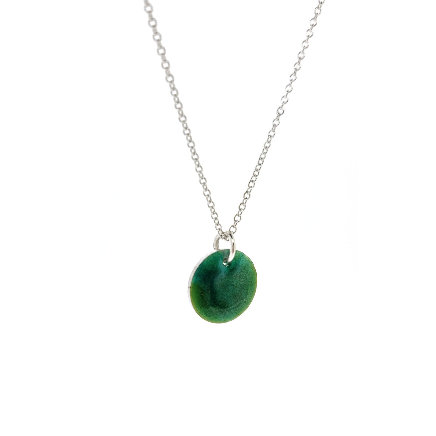 A round silver pendant with a mix of green enamels. On a silver chain.