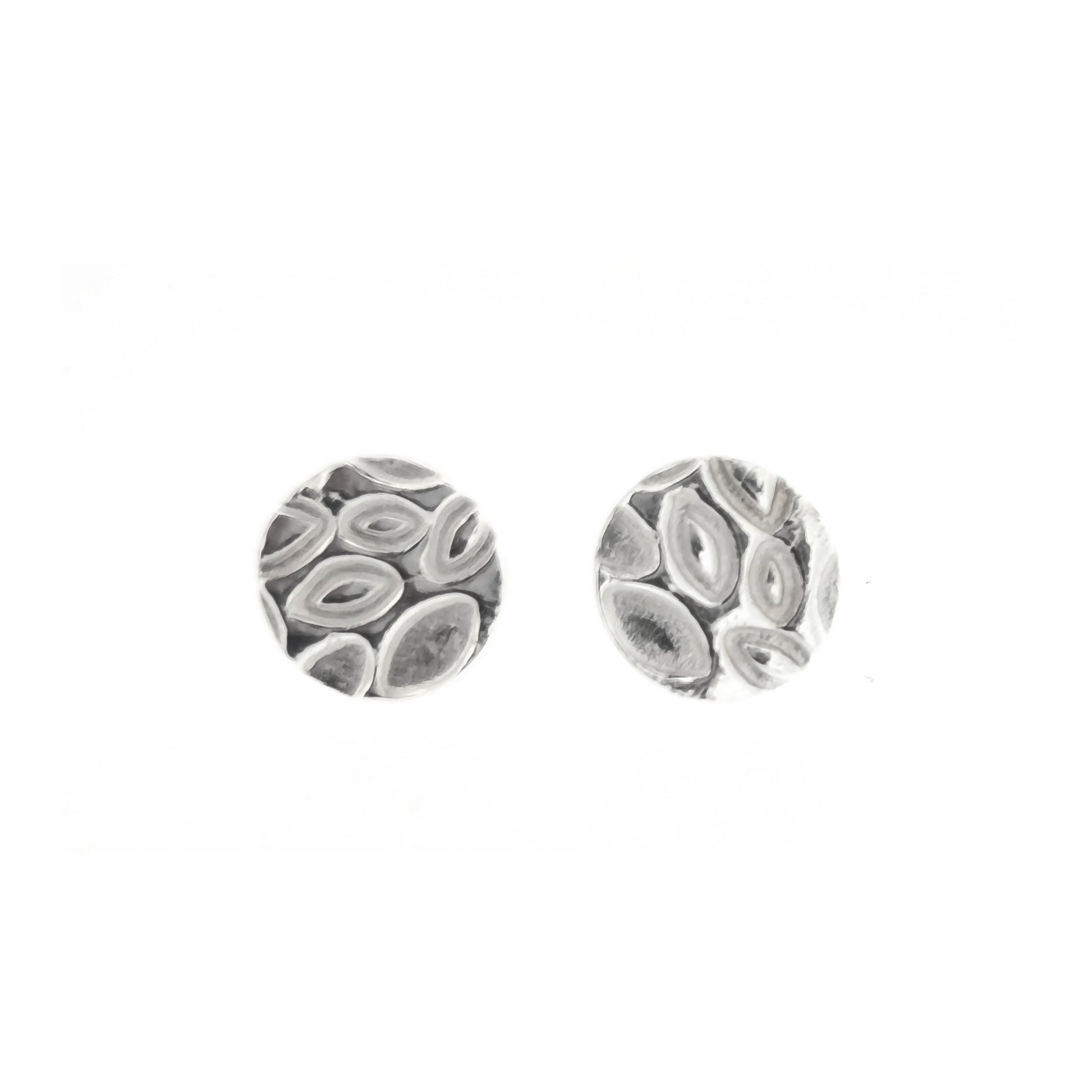 A pair of round silver stud earrings with a marquise (or leaf) shaped pattern on. Shown on slate with flowers.