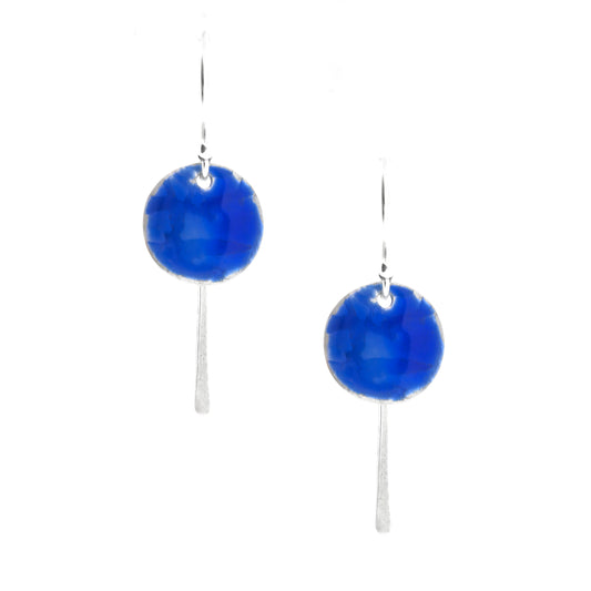 Silver drop earrings featuring a rustic round disc with a lined pattern covered with dark blue enamel.  slim silver tag hangs behind and below. On silver ear hooks.