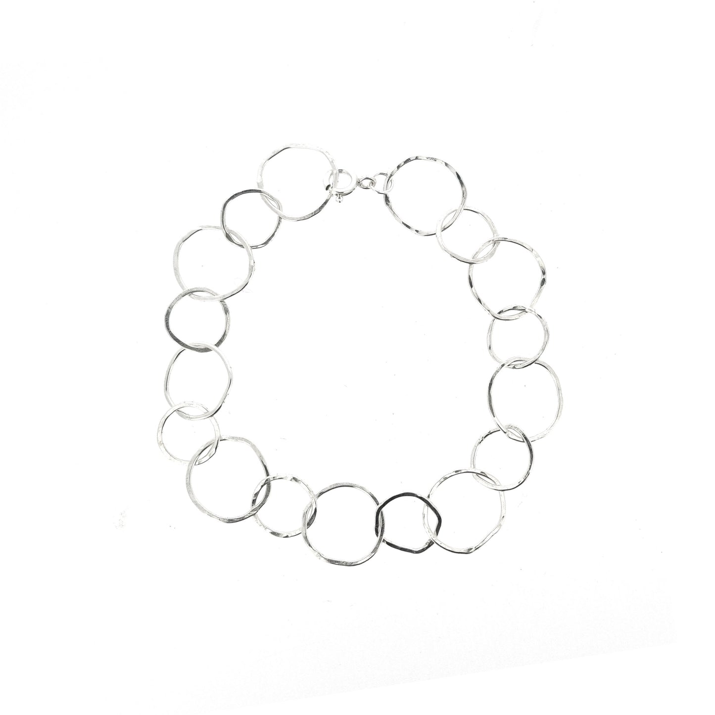 A silver chain link bracelet with delicate links of various sizes in an organic circle shape.