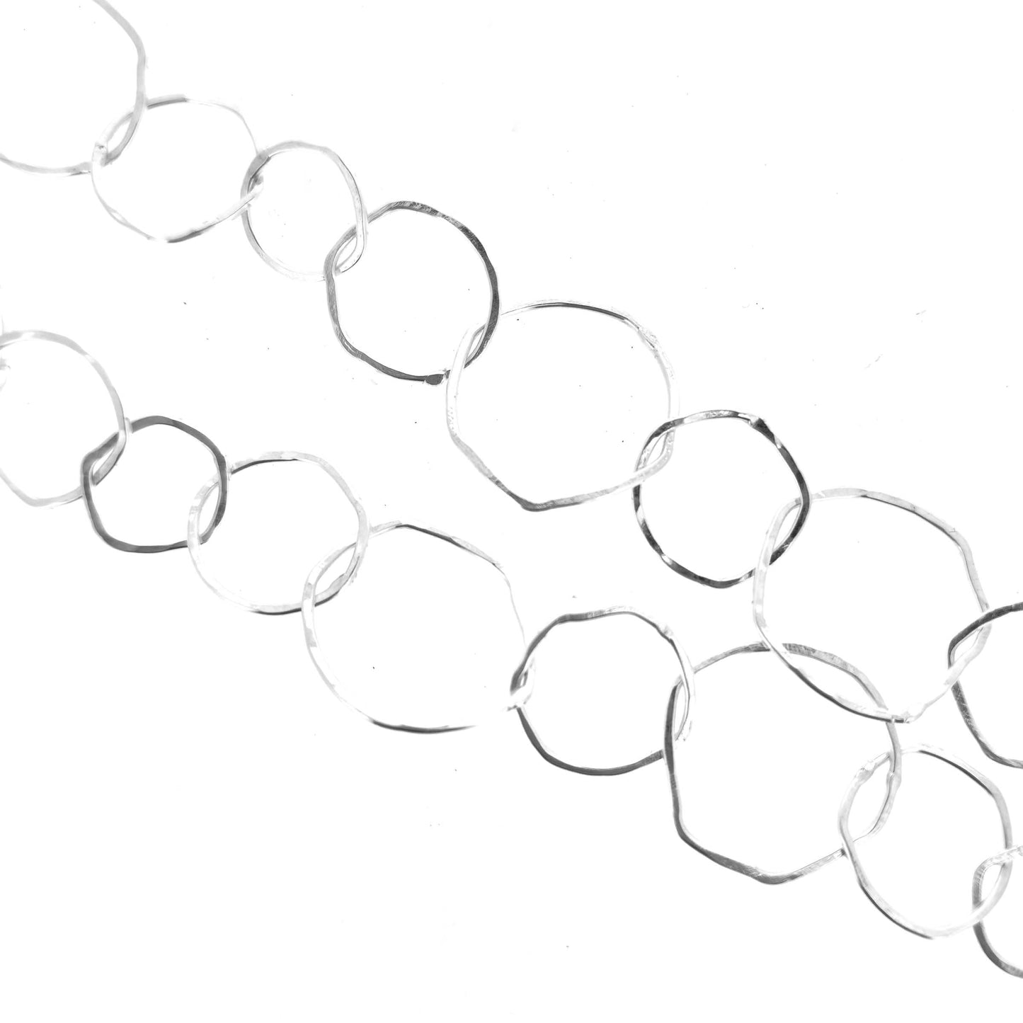 Part of a silver necklace with rustic interlocking circular links on a white back ground
