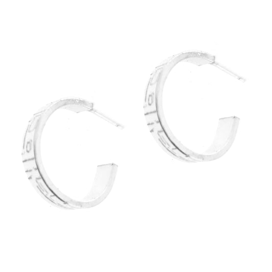 A pair of silver flat hoop earrings with a square and line pattern on.