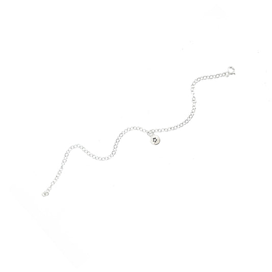 A silver chain bracelet with an organic style round charm with a star engraved on it.