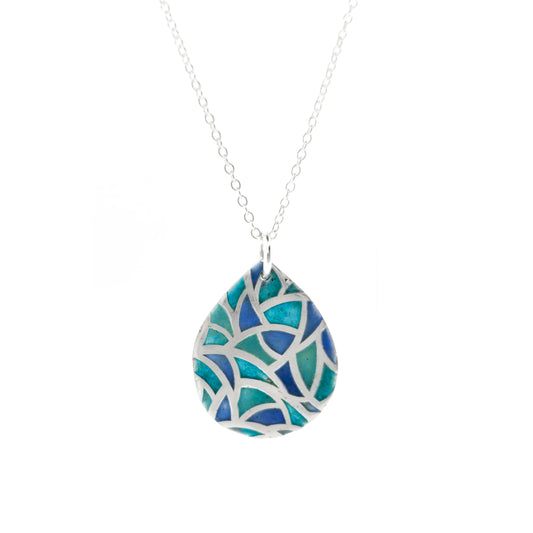 A teardrop shaped silver pendant with geometric cells of blue, green and turquoise enamel. On a silver chain.