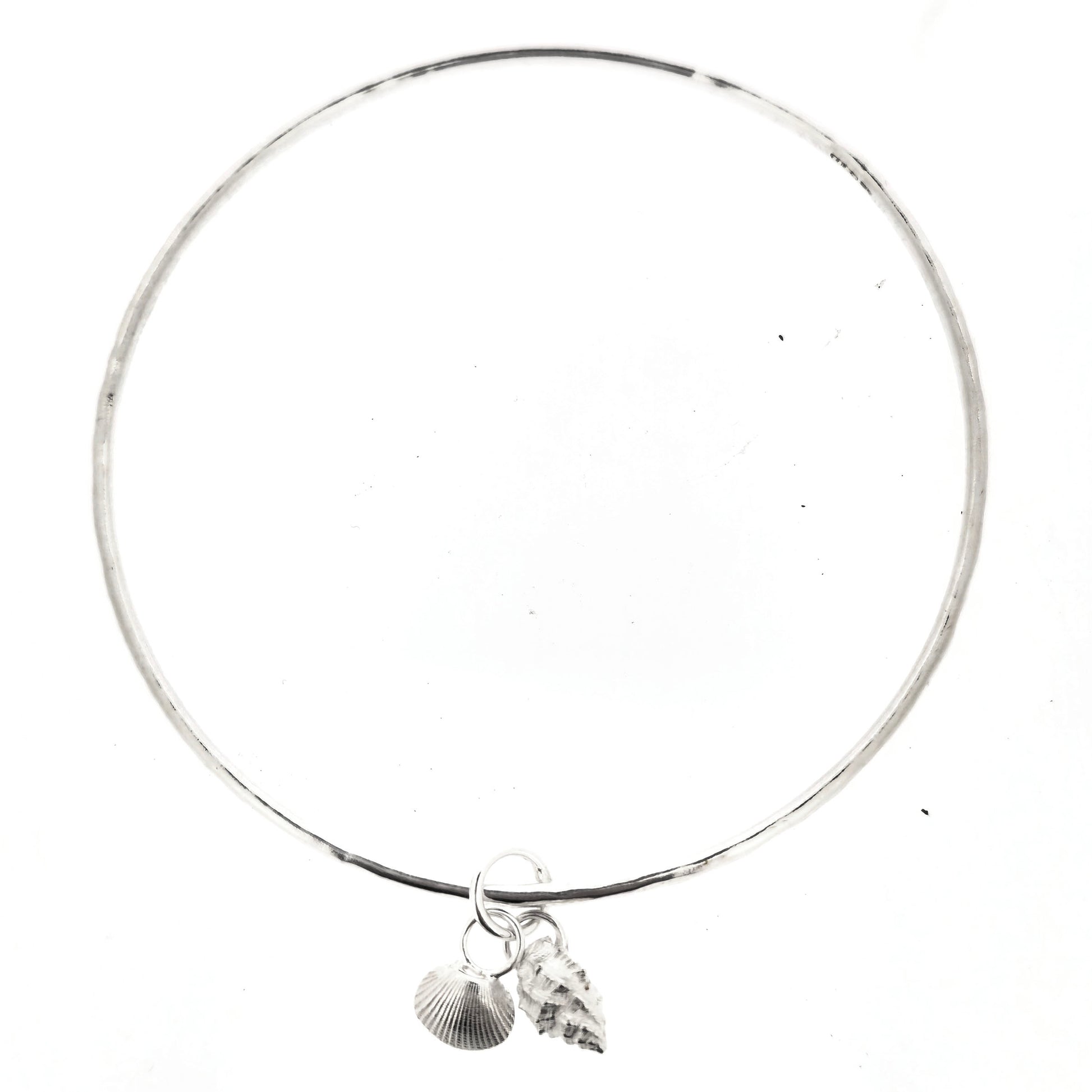 A round silver bangle with 2 seashell charms. 1 cockle shell and 1 periwonkle shell. On a white background. Handmade, Mijoux Jewellery.