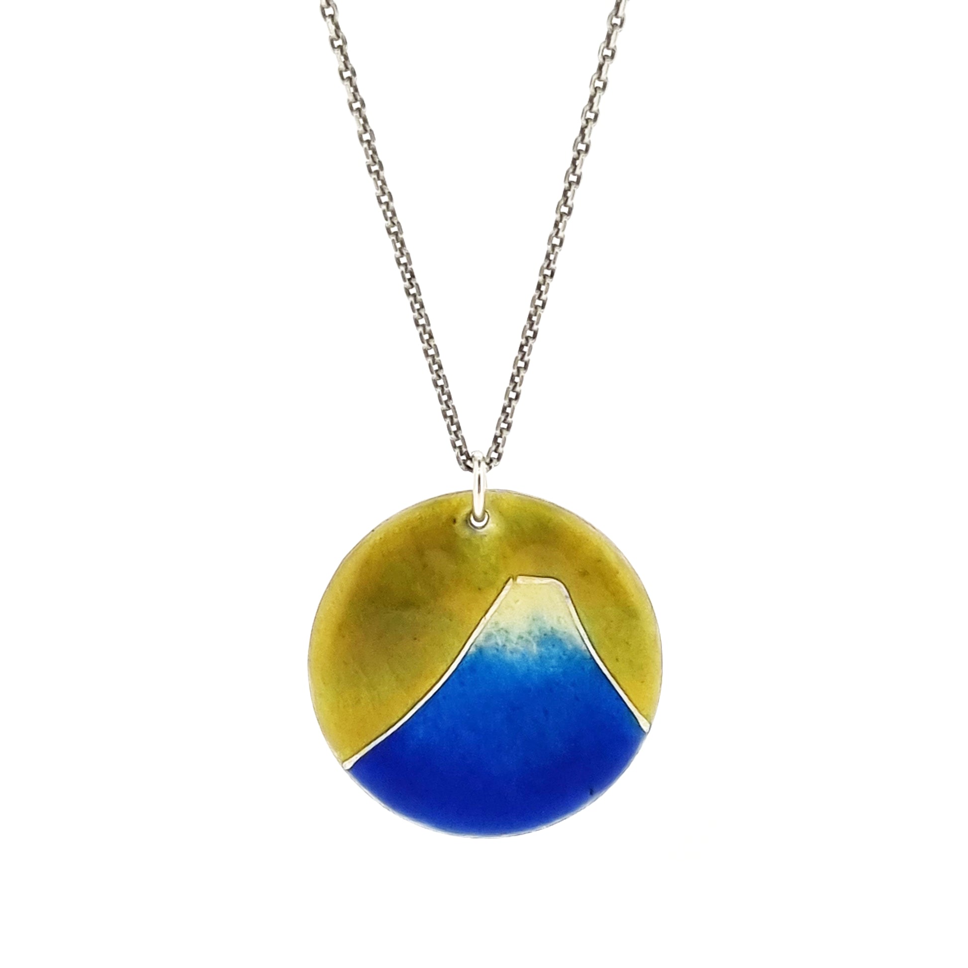 Round silver pendant with a mountain on in graduated blue enamel and a white top and a yellow enamel background. Suspended from a silver chain.