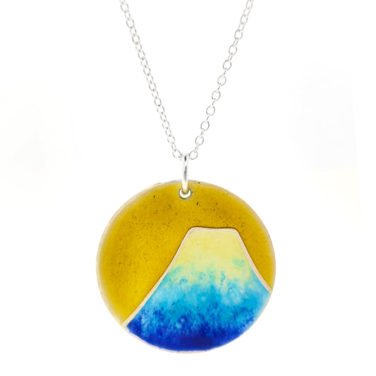 Round silver pendant with a mountain on in graduated blue enamel and a white top and a yellow enamel background. Suspended from a silver chain