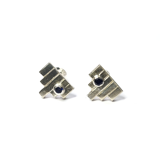 Silver Art Deco style stud earrings with 5 silver lines and off-centre dark blue sapphires.