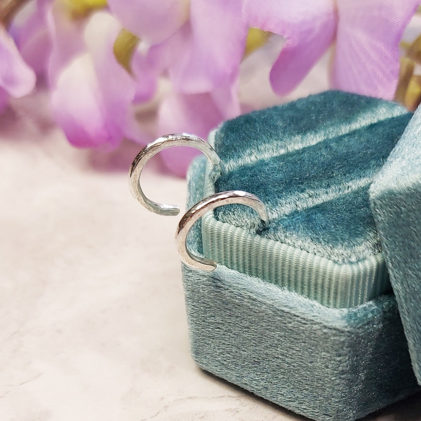 Silver thin hammered hoop earrings - small. Shown pictured in a jewellery box with flowers.