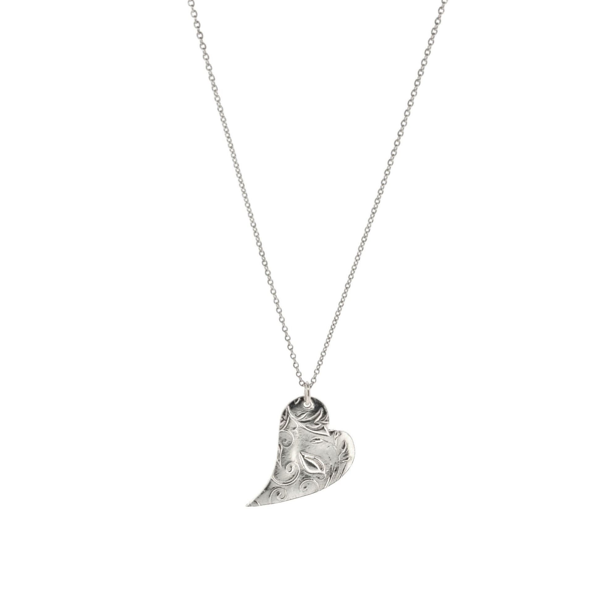 A silver asymmetrical heart pendant with a leaf and vine pattern suspended on a silver chain - large