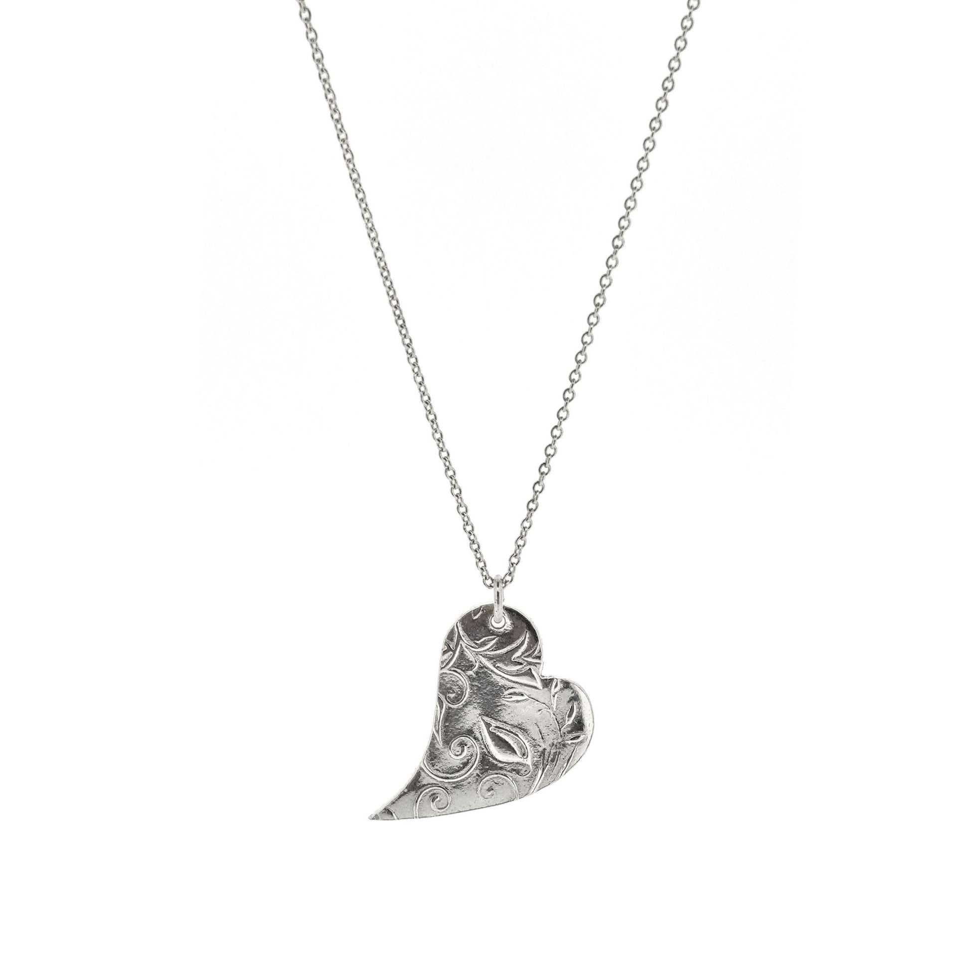 A silver asymmetrical heart pendant with a leaf and vine pattern suspended on a silver chain. - large