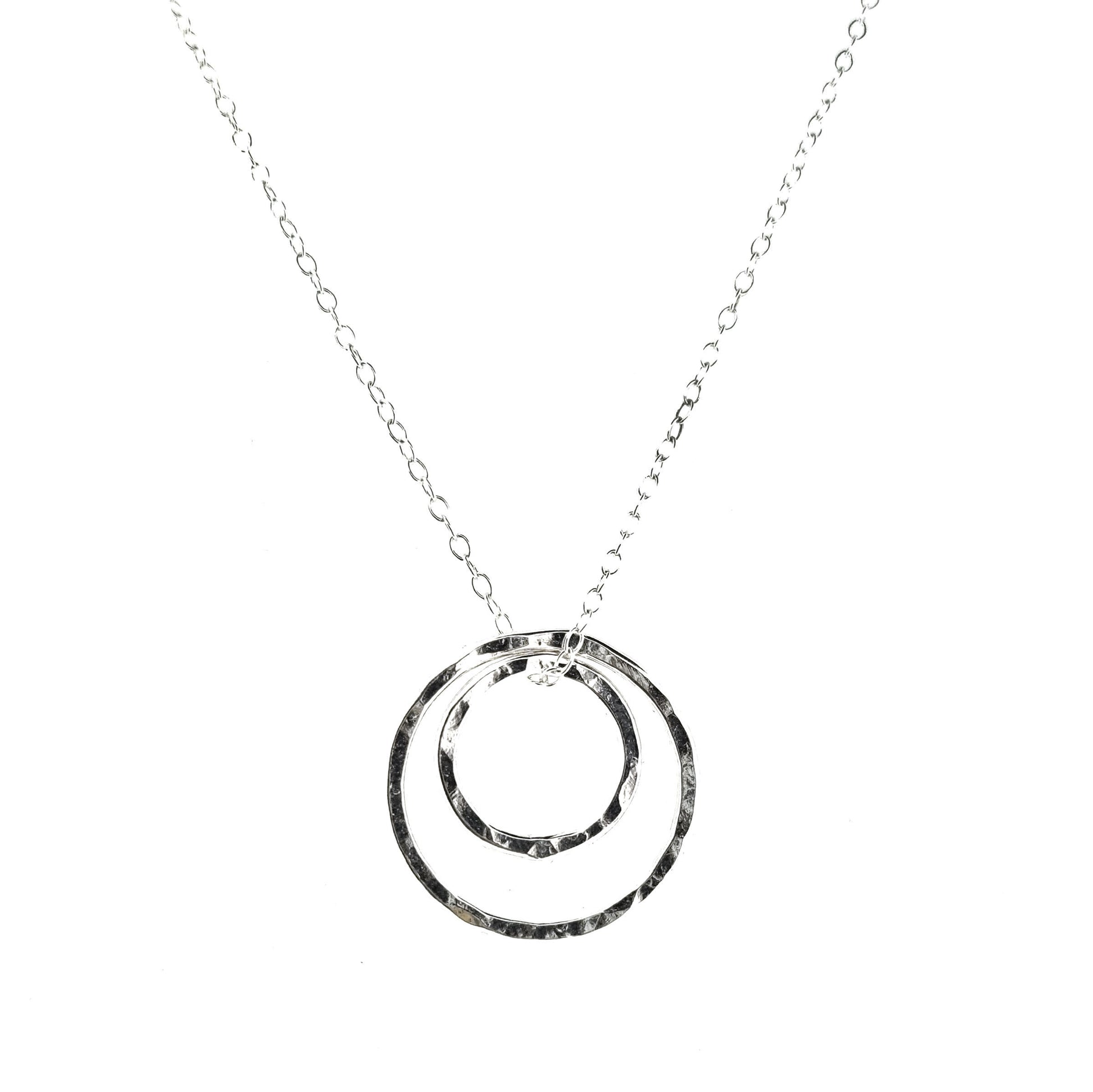 A silver double circle pendant on a silver chain. The circles have a hammered finish.