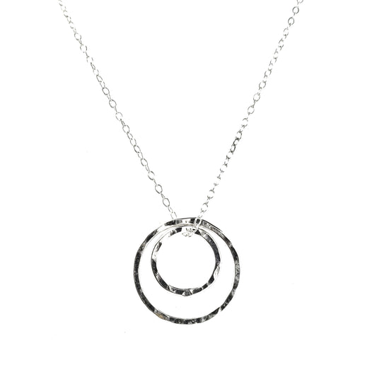 A silver double circle pendant on a silver chain. The circles have a hammered finish.