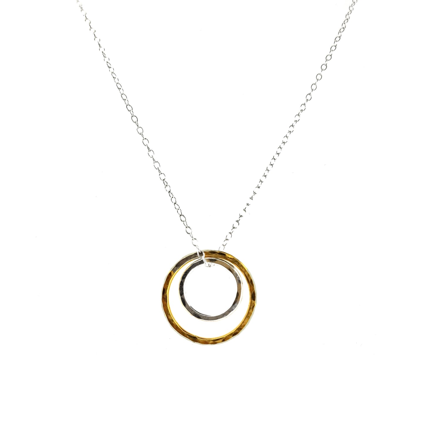 A double circle pendant with an inner silver hammered circle and an outer yellow gold vermeil hammered circle. Suspended on a silver chain.