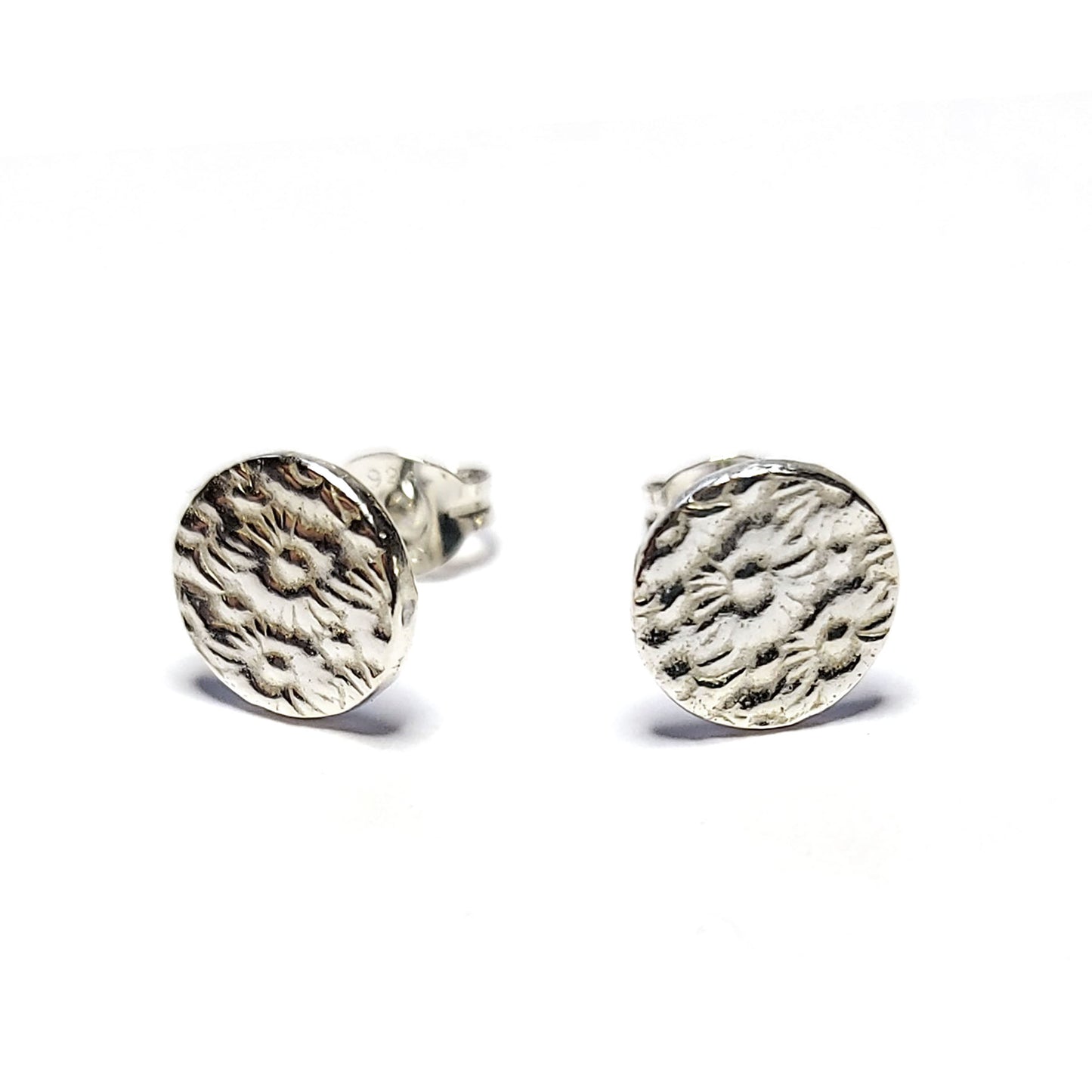 Round silver stud earrings with a pattern of flowers.