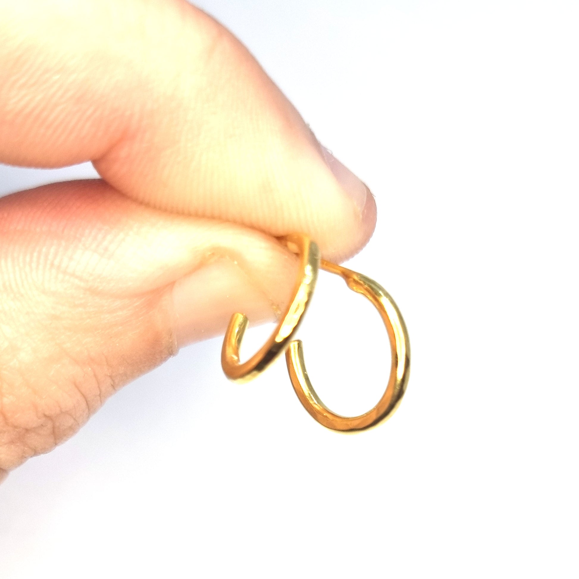 Yellow gold vermeil thin hammered hoop earrings, small. Pictured being held in a hand.