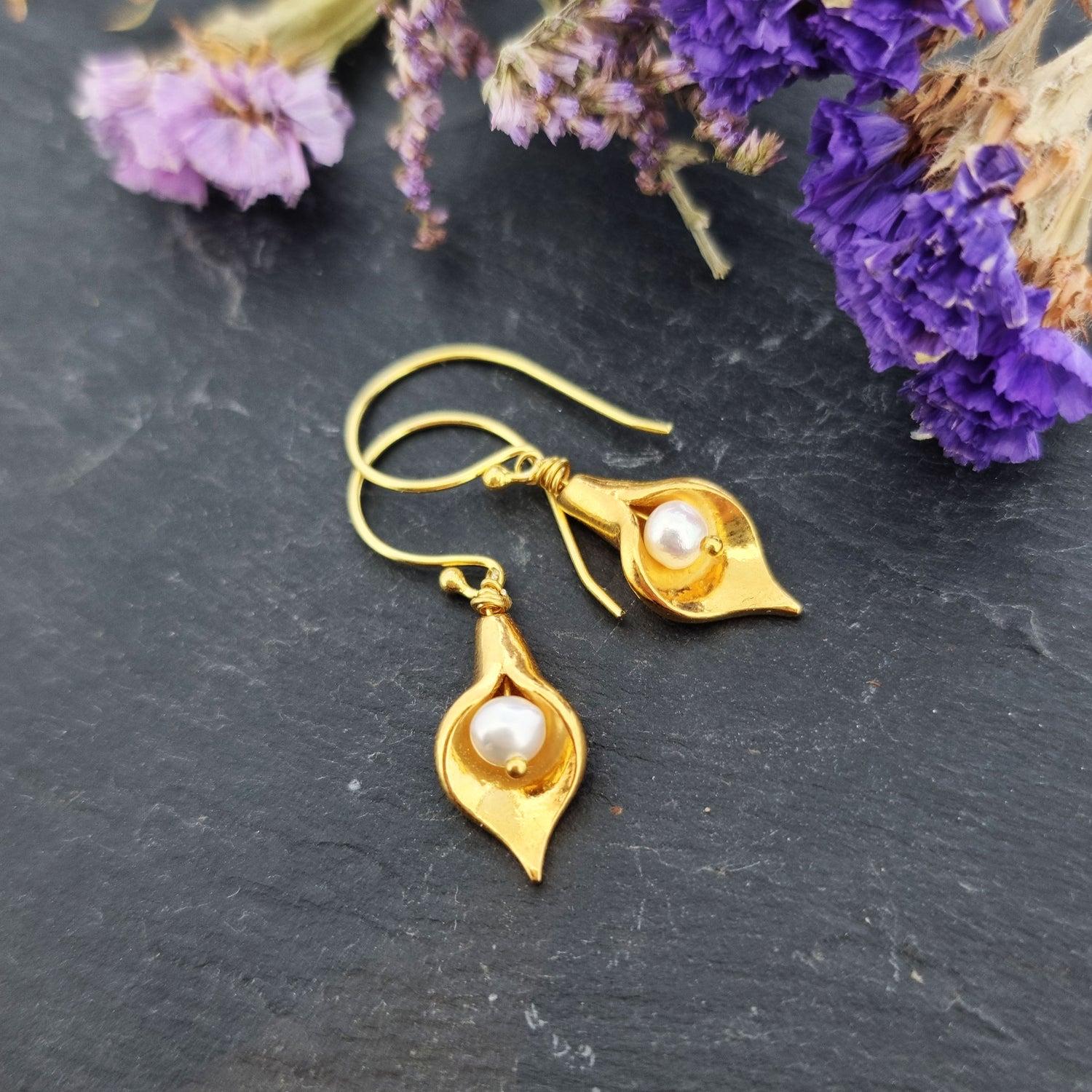 Yellow gold vermeil cala lily drop earrings with freshwater pearls. Pictured with flowers.