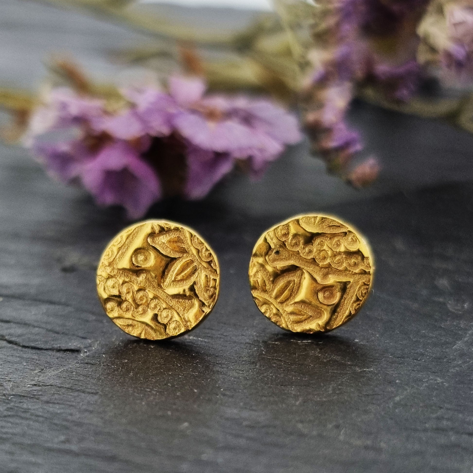 Yellow gold vermeil round patterned stud earrings. Pictured with purple flowers.