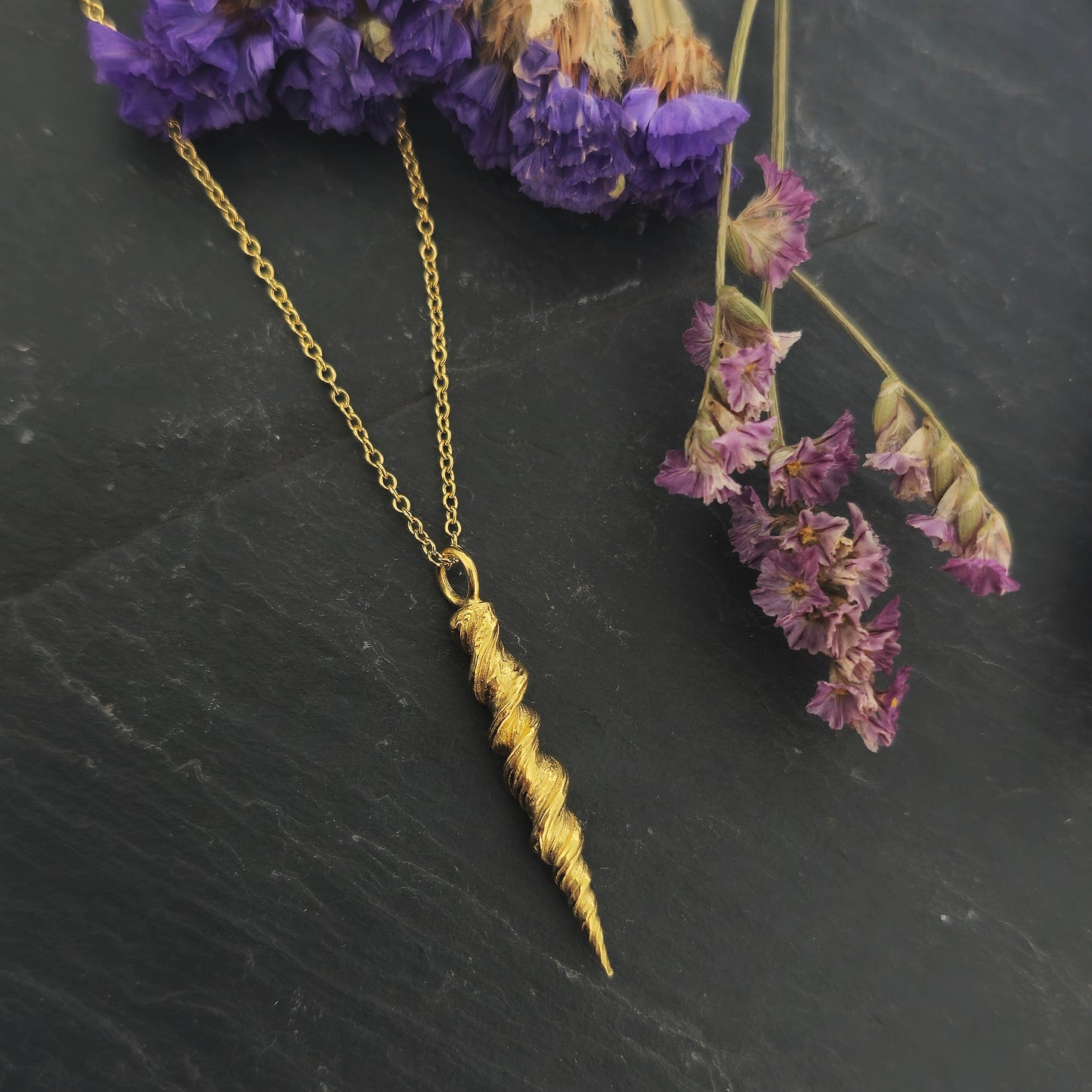 Yellow gold vermeil twist pendant on a yellow gold vermeil chain. Shown on slate with flowers.