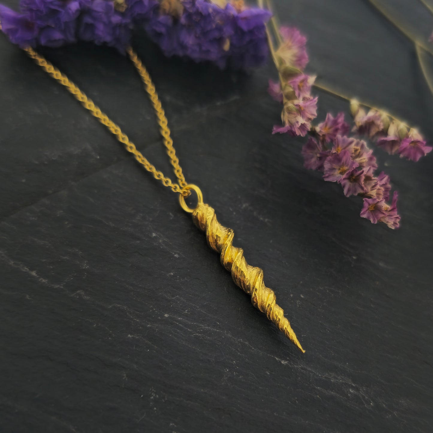 Yellow gold vermeil twist pendant on a yellow gold vermeil chain. Shown on slate with flowers.