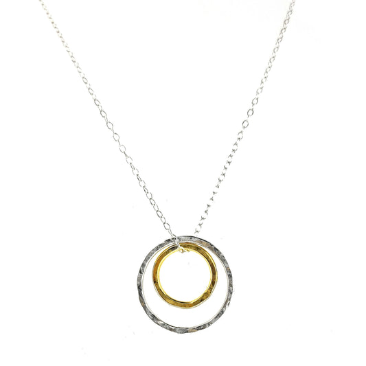 A double circle pendant with an inner yellow gold vermeil hammered circle and an outer silver hammered circle. Suspended on a silver chain.